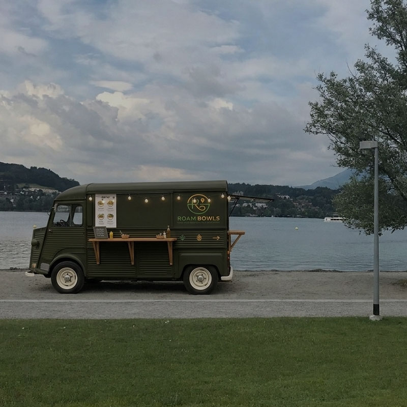 Seitenansicht des dunkelgrünen Roam Bowls Foodtrucks auf einem Kiesweg direkt an der Uffschöti in Luzern.