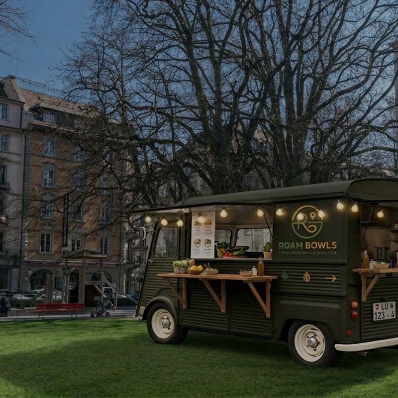 Ein dunkelgrüner Roam Bowls Foodtruck steht bei Vögeligärtli auf einer grossen grünen Wiese.